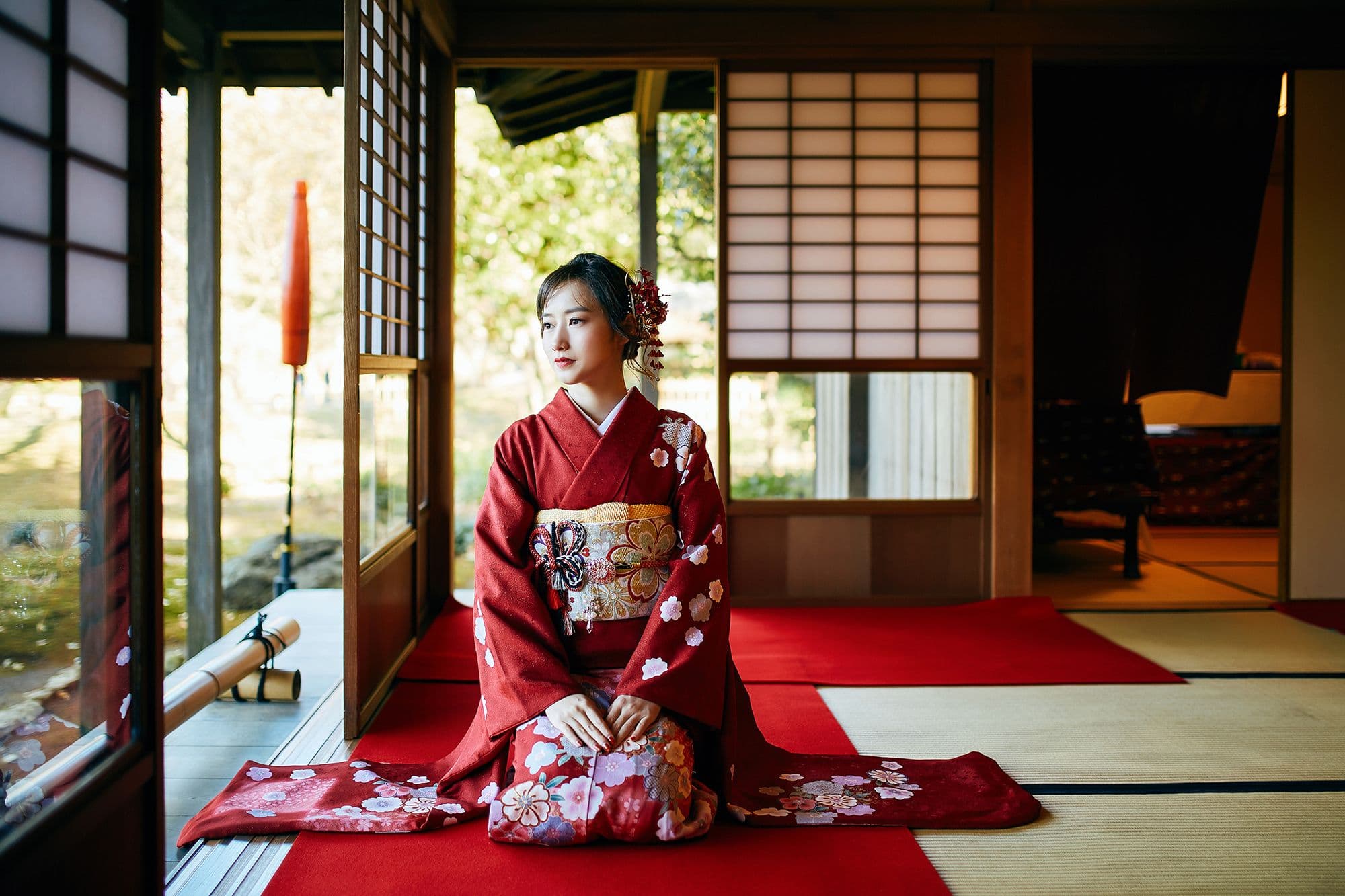 身穿紅色和服的女性端坐在日式榻榻米房間中,展現優雅傳統的日本文化體驗