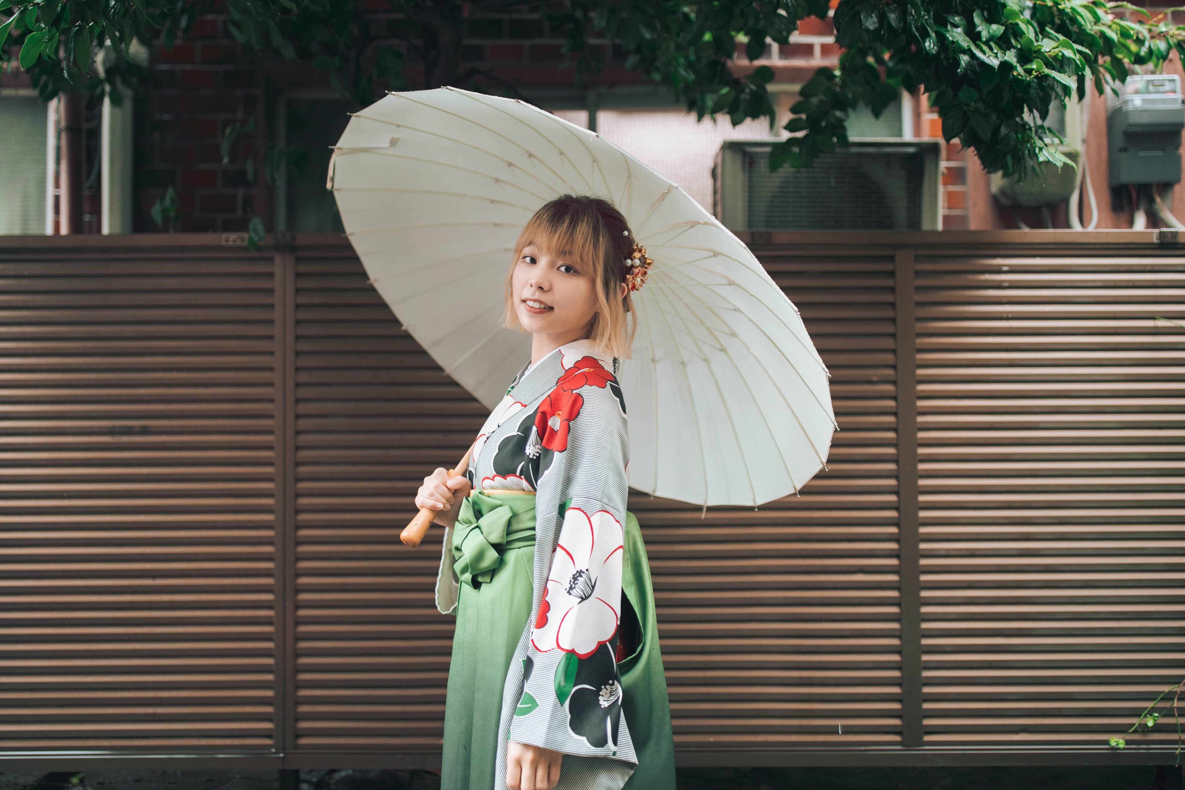 穿著漫風情袴和服的女性撐著和傘,在日本街道中享受充滿和風氛圍的旅遊時光