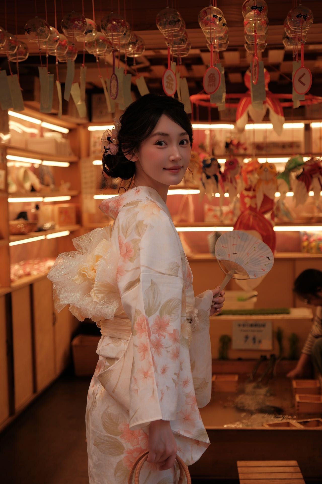 白い花柄浴衣をおしゃれに着こなした女性が、夜の浅草散策を楽しむ様子
